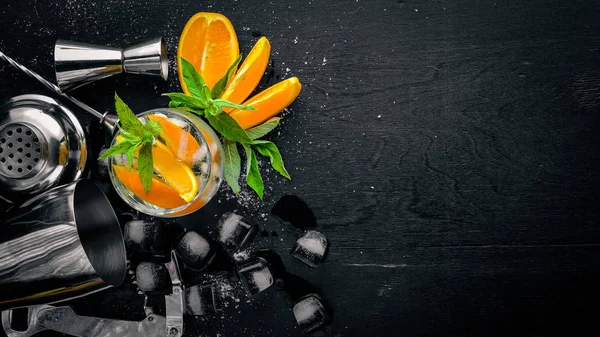 Portakal ve mentol buza, siyah ahşap yüzey ile kokteyl. Üstten Görünüm. Boş alan.