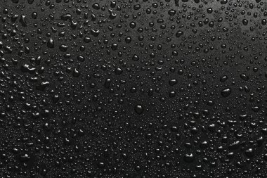 Siyah bir yüzeye düşen su damlaları