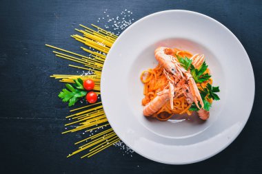 Domates soslu makarna ve kaplan karides. Geleneksel İtalyan yemekleri. Ahşap bir arka plan üzerinde. Üstten Görünüm. Metniniz için boş alan.