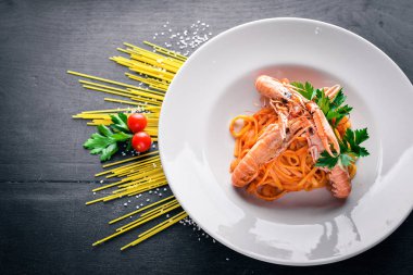 Domates soslu makarna ve kaplan karides. Geleneksel İtalyan yemekleri. Ahşap bir arka plan üzerinde. Üstten Görünüm. Metniniz için boş alan.