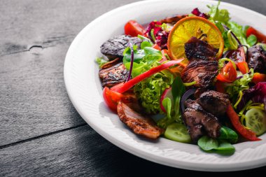 Salata taze salatalık, domates ve yeşillik bir plaka ahşap tahta üzerinde ızgara et ile. Üstten Görünüm. Boş alan.