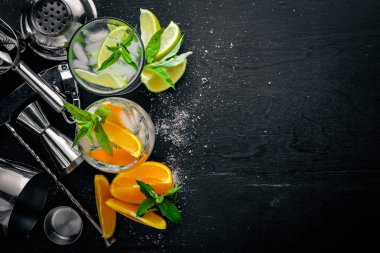 Kokteyller, narenciye ve mentol buza, siyah ahşap yüzey ile yenileniyor. Üstten Görünüm. Boş alan.