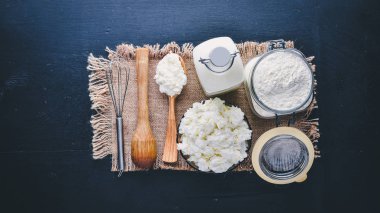 Süt ve süt ürünleri. Peynir, peynir, süt, ekşi krema, siyah ahşap zemin. Üstten Görünüm. Boş alan.