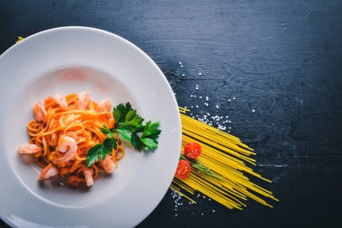 Karides ve domates soslu makarna. Geleneksel İtalyan yemekleri. Ahşap bir arka plan üzerinde. Üstten Görünüm. Metniniz için boş alan.