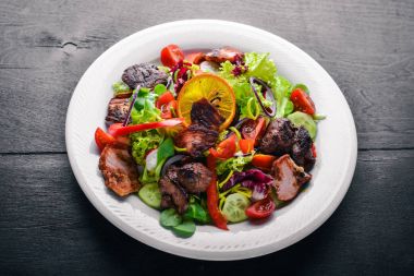 Salata taze salatalık, domates ve yeşillik bir plaka ahşap tahta üzerinde ızgara et ile. Üstten Görünüm. Boş alan.