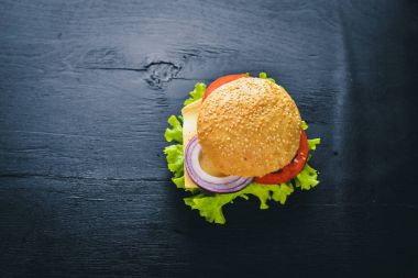 Peynir, et, domates ve soğan ve otlar ile hamburger. Ahşap arka plan üzerinde. Üstten Görünüm. Boş alan.