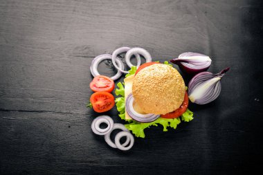 Peynir, et, domates ve soğan ve otlar ile hamburger. Ahşap arka plan üzerinde. Üstten Görünüm. Boş alan.