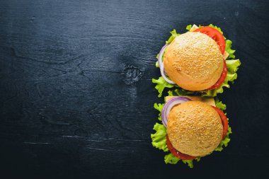 Peynir, et, domates ve soğan ve otlar ile hamburger. Ahşap arka plan üzerinde. Üstten Görünüm. Boş alan.