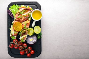 Somon Bruschetta otlar ve parmesan peyniri ekmeğin. Soğuk aperatifler. İtalyan mutfağı. Ahşap arka plan üzerinde.