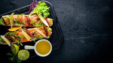 Somon Bruschetta otlar ve parmesan peyniri ekmeğin. Soğuk aperatifler. İtalyan mutfağı. Ahşap arka plan üzerinde.