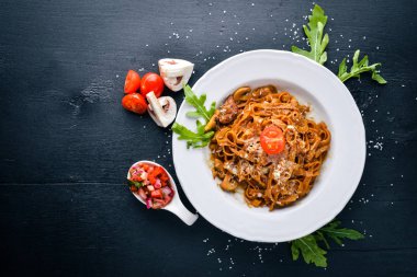 Kiraz domates, zeytin ve parmesan peyniri ile mantarlı makarna. İtalyan yemeği. Bir siyah ahşap yüzeye. Metniniz için boş alan. Üstten Görünüm.