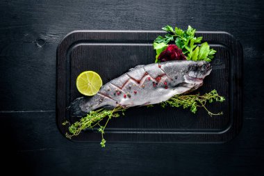 Balık alabalık aromatik otlar ve baharatlar ile. Ahşap arka plan üzerinde.