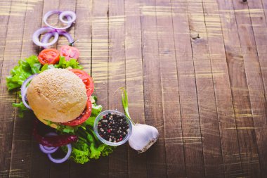 Peynir, et, domates ve soğan ve otlar ile hamburger. Ahşap arka plan üzerinde. Üstten Görünüm. Boş alan.
