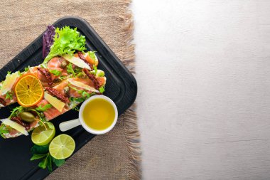 Somon Bruschetta otlar ve parmesan peyniri ekmeğin. Soğuk aperatifler. İtalyan mutfağı. Ahşap arka plan üzerinde.