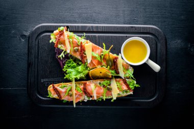 Somon Bruschetta otlar ve parmesan peyniri ekmeğin. Soğuk aperatifler. İtalyan mutfağı. Ahşap arka plan üzerinde.