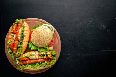 Sosisli sandviç ve hamburger ile peynir, et ve Yeşiller ahşap arka plan üzerinde. Üstten Görünüm. Boş alan.