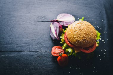 Peynir, et, domates ve soğan ve otlar ile hamburger. Ahşap arka plan üzerinde. Üstten Görünüm. Boş alan.