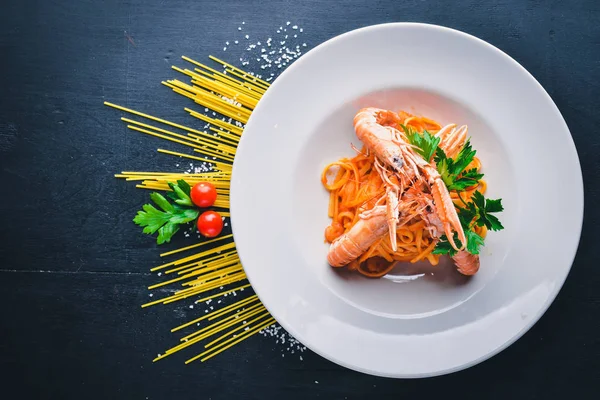 Domates soslu makarna ve kaplan karides. Geleneksel İtalyan yemekleri. Ahşap bir arka plan üzerinde. Üstten Görünüm. Metniniz için boş alan.