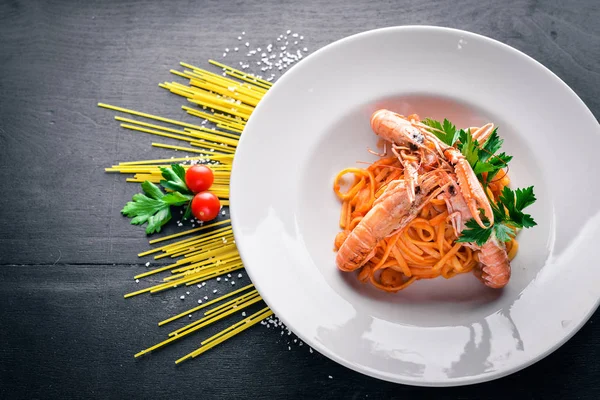 Domates soslu makarna ve kaplan karides. Geleneksel İtalyan yemekleri. Ahşap bir arka plan üzerinde. Üstten Görünüm. Metniniz için boş alan.