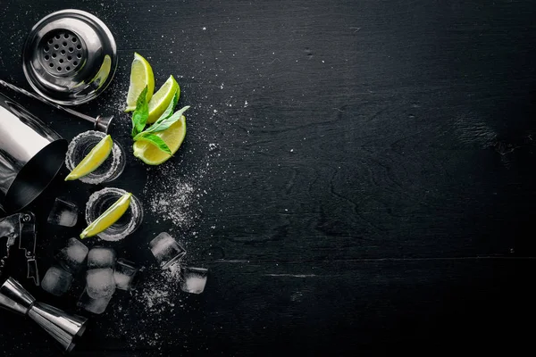 Tequila con cal y hielo, sobre una superficie de madera negra. Vista superior. Espacio libre . —  Fotos de Stock