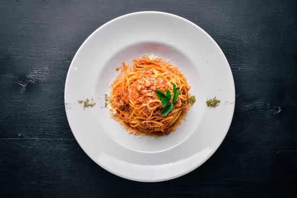 Domates sos ve parmesan peynirli makarna. Geleneksel İtalyan yemekleri. Ahşap bir arka plan üzerinde. Üstten Görünüm. Metniniz için boş alan.