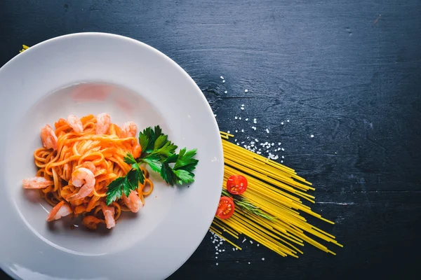 Karides ve domates soslu makarna. Geleneksel İtalyan yemekleri. Ahşap bir arka plan üzerinde. Üstten Görünüm. Metniniz için boş alan.