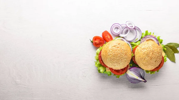 Hamburger with cheese, meat, tomatoes and onions and herbs. On Wooden background. Top view. Free space. — Stock Photo, Image