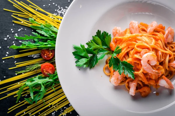 Karides ve domates soslu makarna. Geleneksel İtalyan yemekleri. Ahşap bir arka plan üzerinde. Üstten Görünüm. Metniniz için boş alan.