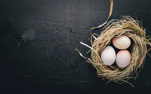 Tavuk yumurta yuvada. Ahşap resmi siyah bir arka plan için. Üstten Görünüm. Boş alan.