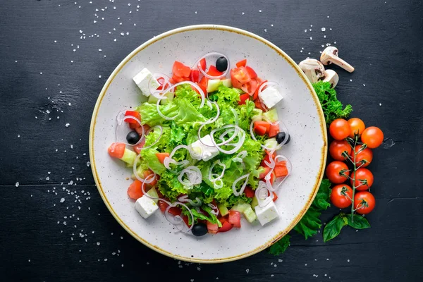 Griekse salade van verse groenten en kaas. Op een houten achtergrond. Bovenaanzicht. Vrije ruimte voor uw tekst. — Stockfoto