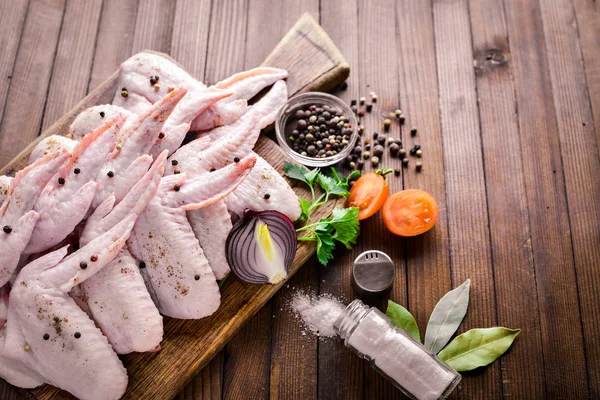 Baharat ile çiğ tavuk kanatları. Ahşap yüzeyde. Üstten Görünüm.