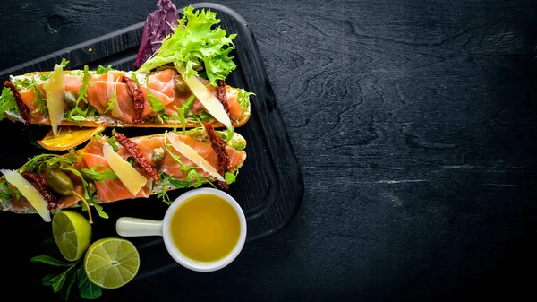Somon Bruschetta otlar ve parmesan peyniri ekmeğin. Soğuk aperatifler. İtalyan mutfağı. Ahşap arka plan üzerinde.