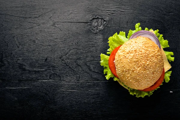 Peynir, et, domates ve soğan ve otlar ile hamburger. Ahşap arka plan üzerinde. Üstten Görünüm. Boş alan.
