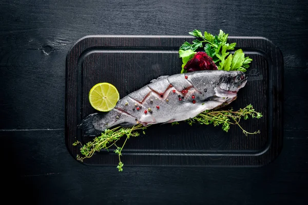 Balık alabalık aromatik otlar ve baharatlar ile. Ahşap arka plan üzerinde.