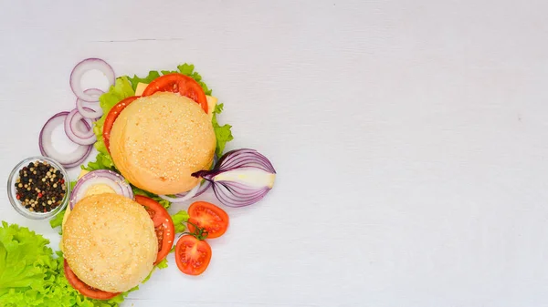 Hambúrguer com queijo, carne, tomate e cebola e ervas. Sobre fundo de madeira. Vista superior. Espaço livre . — Fotografia de Stock