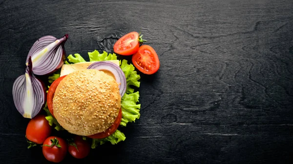Peynir, et, domates ve soğan ve otlar ile hamburger. Ahşap arka plan üzerinde. Üstten Görünüm. Boş alan.