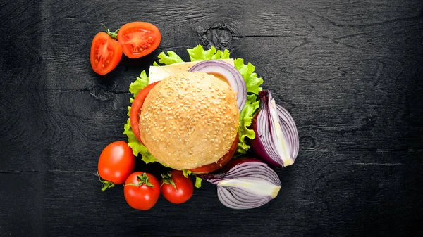 Peynir, et, domates ve soğan ve otlar ile hamburger. Ahşap arka plan üzerinde. Üstten Görünüm. Boş alan.