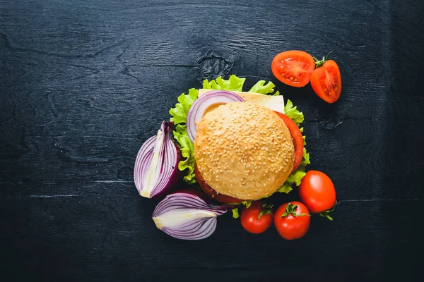 Peynir, et, domates ve soğan ve otlar ile hamburger. Ahşap arka plan üzerinde. Üstten Görünüm. Boş alan.