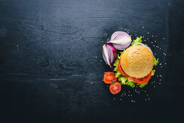 Peynir, et, domates ve soğan ve otlar ile hamburger. Ahşap arka plan üzerinde. Üstten Görünüm. Boş alan.