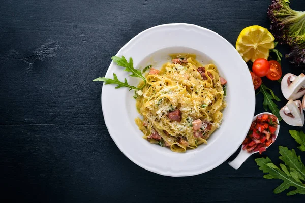 Pastırma, domates, zeytin ve parmesan peyniri ile mantarlı makarna. İtalyan yemeği. Bir siyah ahşap yüzeye. Metniniz için boş alan. Üstten Görünüm.