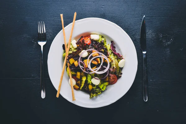 Izgara sebze salatası, mantar, beyaz peynir ve zeytin yağı. Bir siyah ahşap yüzeye. Metniniz için boş alan. Üstten Görünüm.