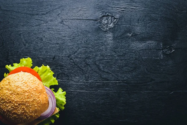 Peynir, et, domates ve soğan ve otlar ile hamburger. Ahşap arka plan üzerinde. Üstten Görünüm. Boş alan.
