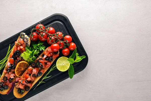 Bruschetta domates, zeytin, otlar ve parmesan peyniri ekmeğin. Soğuk aperatifler. İtalyan mutfağı. Ahşap arka plan üzerinde.