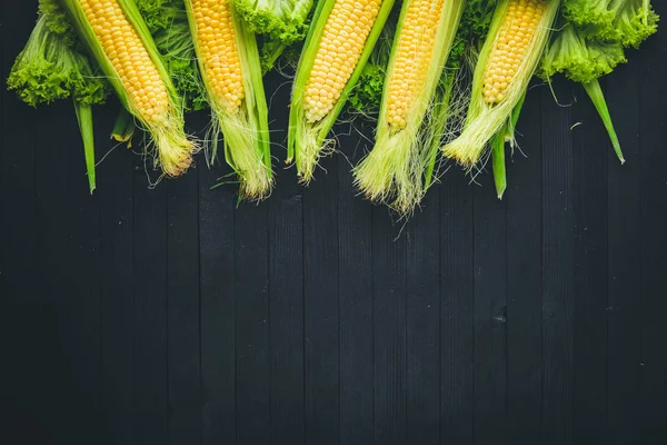 Mısır. Çiğ sebze siyah bir ahşap zemin üzerine. Üstten Görünüm. Metniniz için boş alan.
