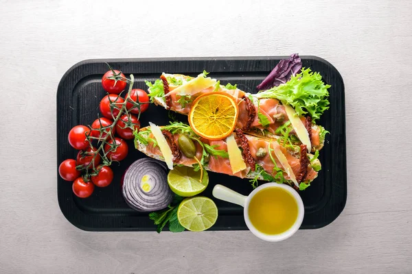 Somon Bruschetta otlar ve parmesan peyniri ekmeğin. Soğuk aperatifler. İtalyan mutfağı. Ahşap arka plan üzerinde.