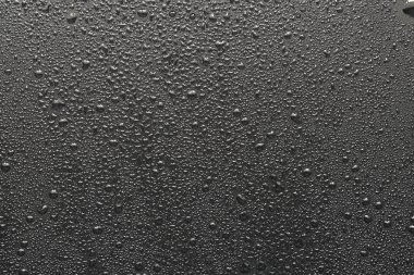 Siyah bir yüzeye düşen su damlaları