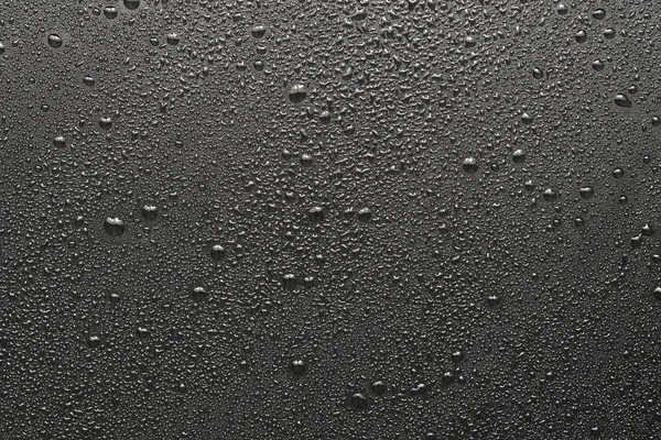 Siyah bir yüzeye düşen su damlaları