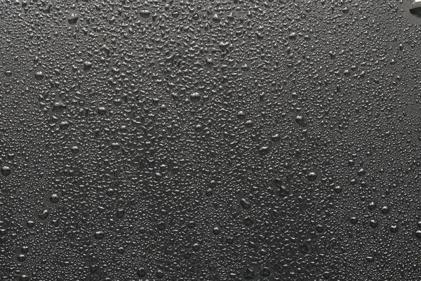 Siyah bir yüzeye düşen su damlaları