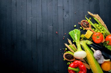 Büyük bir seçim çiğ taze sebze ve baharat. Siyah ahşap arka plan üzerinde. Üstten Görünüm. Metniniz için boş alan.