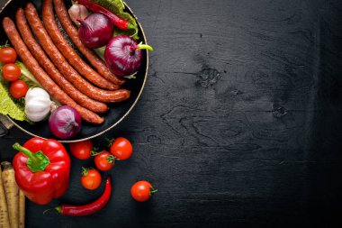Taze sebze ile bir tavada ızgara sosis. Siyah yüzeyi ahşap. Üstten Görünüm.